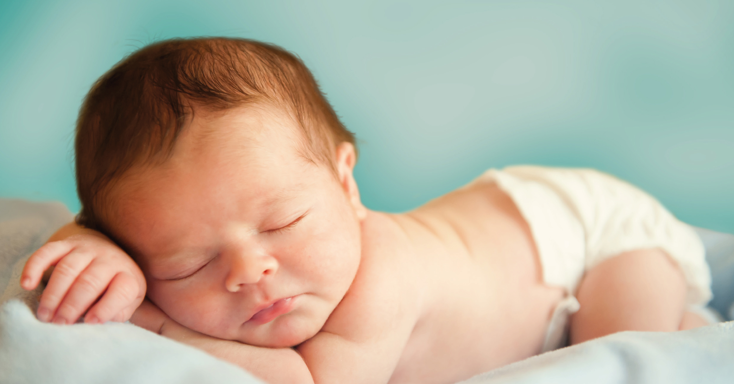 Baby das auf dem Bauch liegend auf seinem Arm schläft